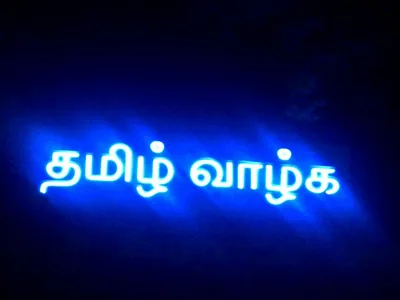 An LED information board glows with Tamil text at night.