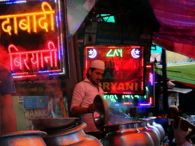 A neon sign spells a biryani shop name at a food stall in Delhi.