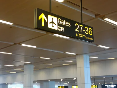 Overhead wayfinding signs point to the gates at Delhi airport.