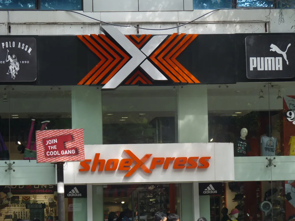 ShoeXpress fascia in Pune with a tilted red board that needs repair.